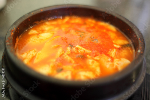 Korean spicy tofu soup in a stone bowl.
