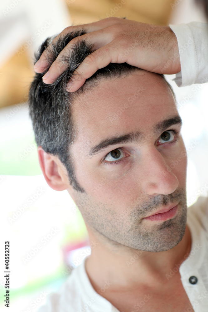 Obraz premium Man in front of mirrror looking at his hair