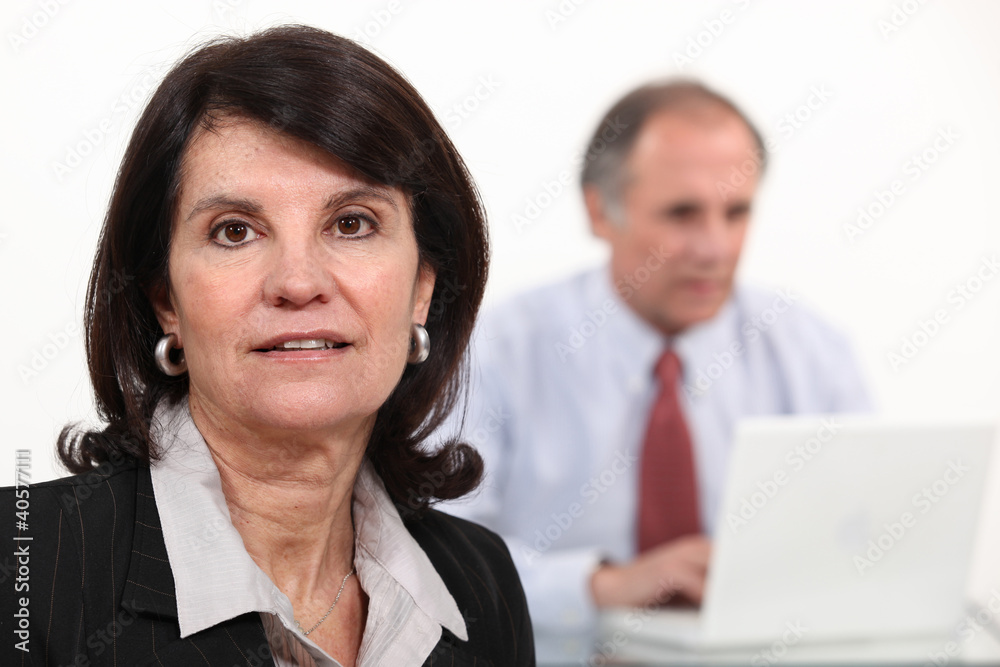 Mature businesswoman and man using a laptop