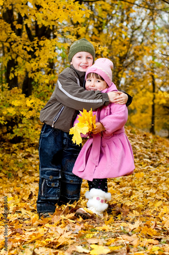 Little boy and girl play in a park in autumn
