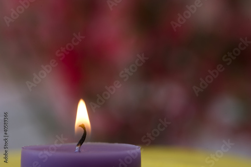 A purple candle in front of pink backround