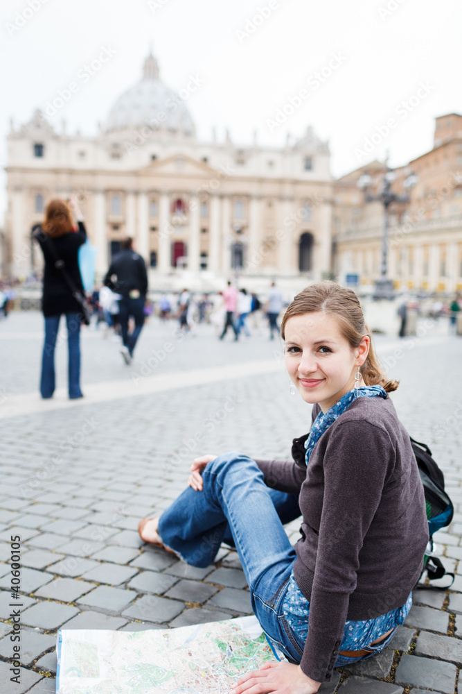 Fototapeta premium Pretty young female tourist studying a map at St. Peter's square