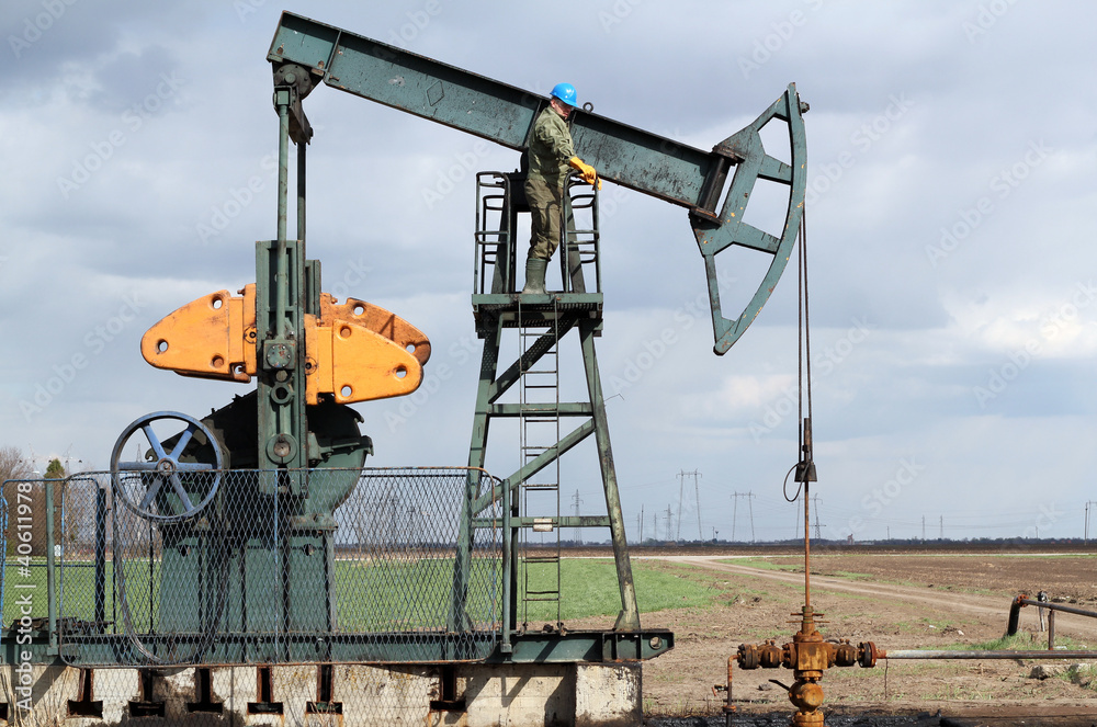oil and fuel industry oil worker standing on the pump jack oil and fuel industry oil worker standing on the pump jack