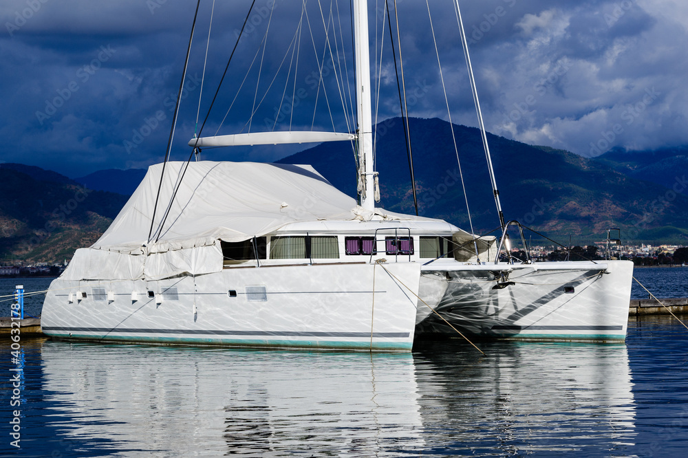 Fototapeta premium Sailing catamaran morred. Heavy sky background and reflections