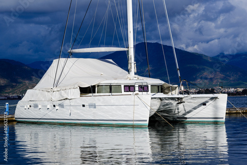 Sailing catamaran morred. Heavy sky background and reflections