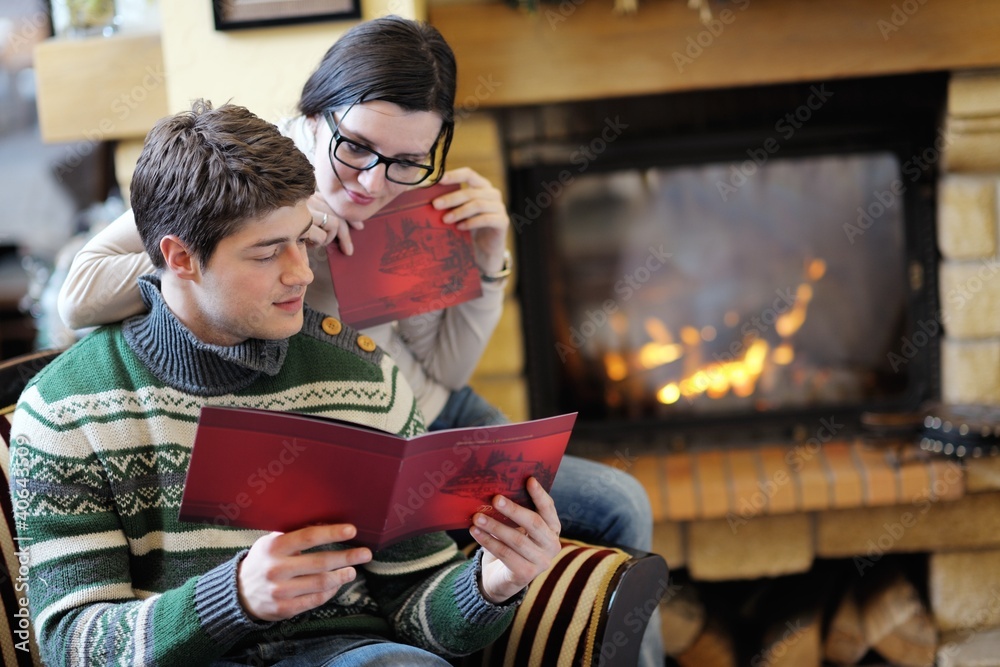 Young romantic couple relax on sofa in front of fireplace at hom