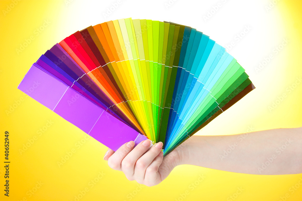 Obraz premium hand holding bright palette of colors on yellow background