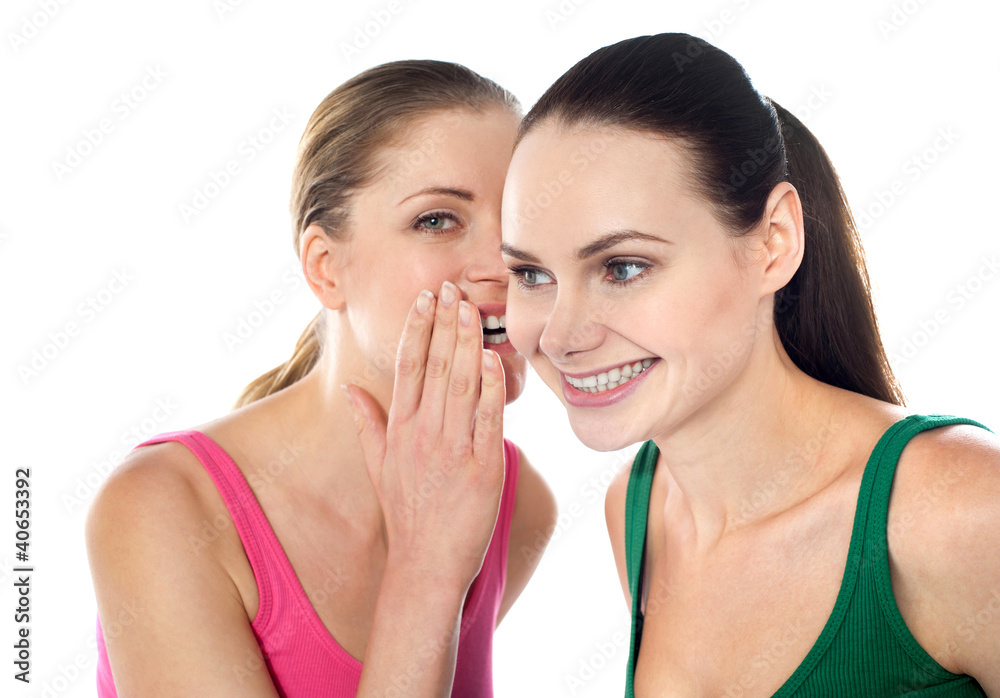 Young beautiful girl whispering secret in her friends ear Young beautiful girl whispering secret in her friends ear