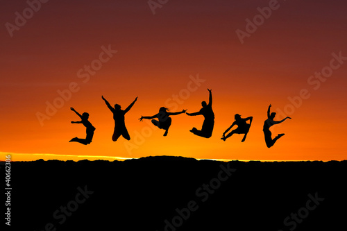 silhouette of friends jumping in sunset