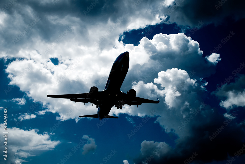 Obraz premium High contrast photo of landing plane with clouds behind