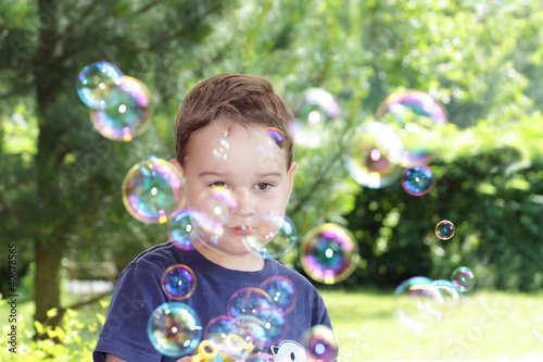 Little boy in the summer park blowing bubbles