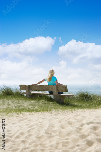 Frau auf einer Bank am Meer