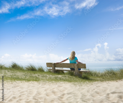 Frau auf einer Bank am Meer