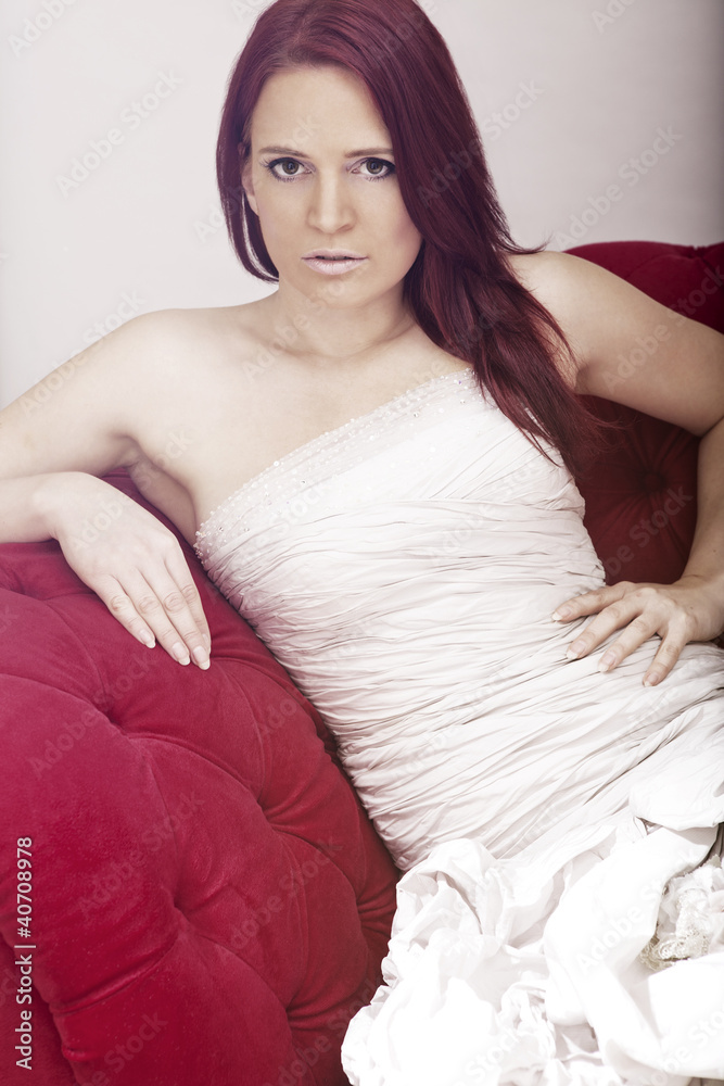 Naklejka premium young red haired beautiful bride on red sofa