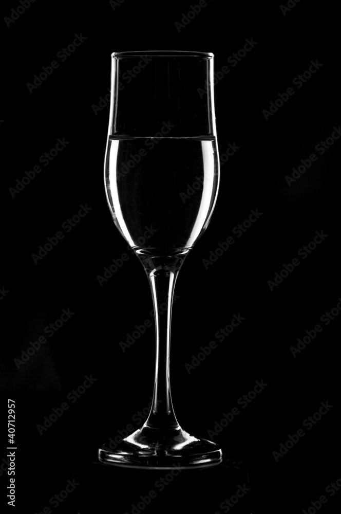 Transparent wine glass filled with water on black