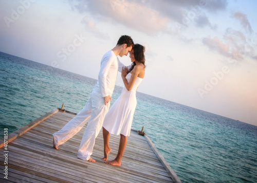 Perfekt happy love couple in white clothes on a jetty (Maldives)