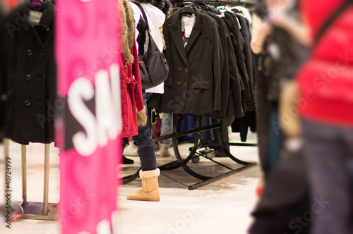 Sale stand and jackets, customers in mall
