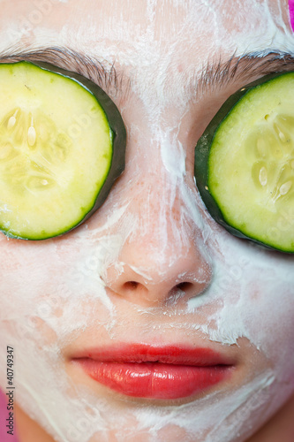 Closeup photo of girl with cucumbers on her eyes and facial mask