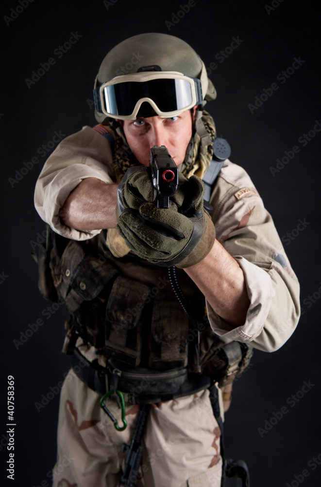 Soldier pointing gun against black background.