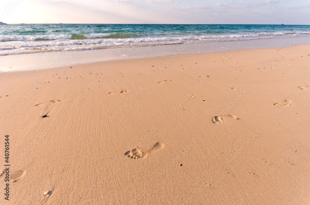 sandy beach with lots of footprints and a blue sky with clouds sandy beach with lots of footprints and a blue sky with clouds