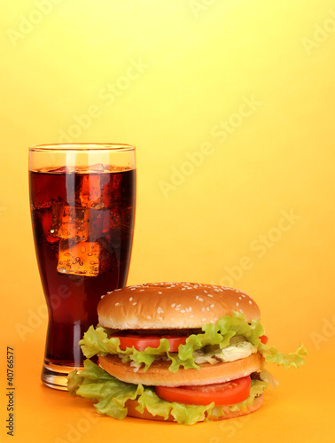 Big and tasty hamburger with cola on yellow background