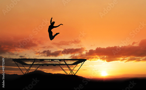 silhouette of female gymnast on trampoline in sunset
