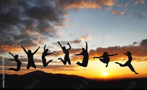 silhouette of friends jumping in sunset