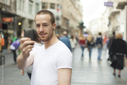 Guy with smartphone take photo on street