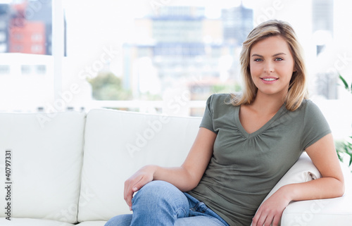 Woman smiling while sitting on couch with crossed legs