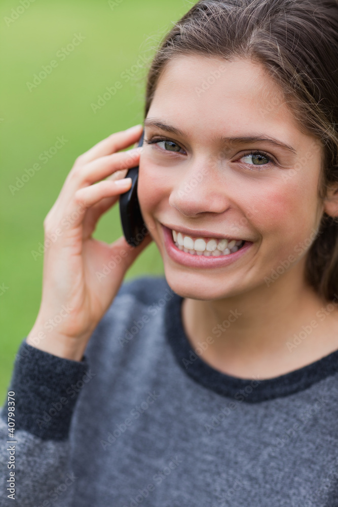 Teenage girl calling with her mobile phone while looking at the Teenage girl calling with her mobile phone while looking at the