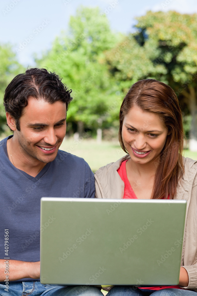 Two friends smiling as they watch something on a tablet Two friends smiling as they watch something on a tablet