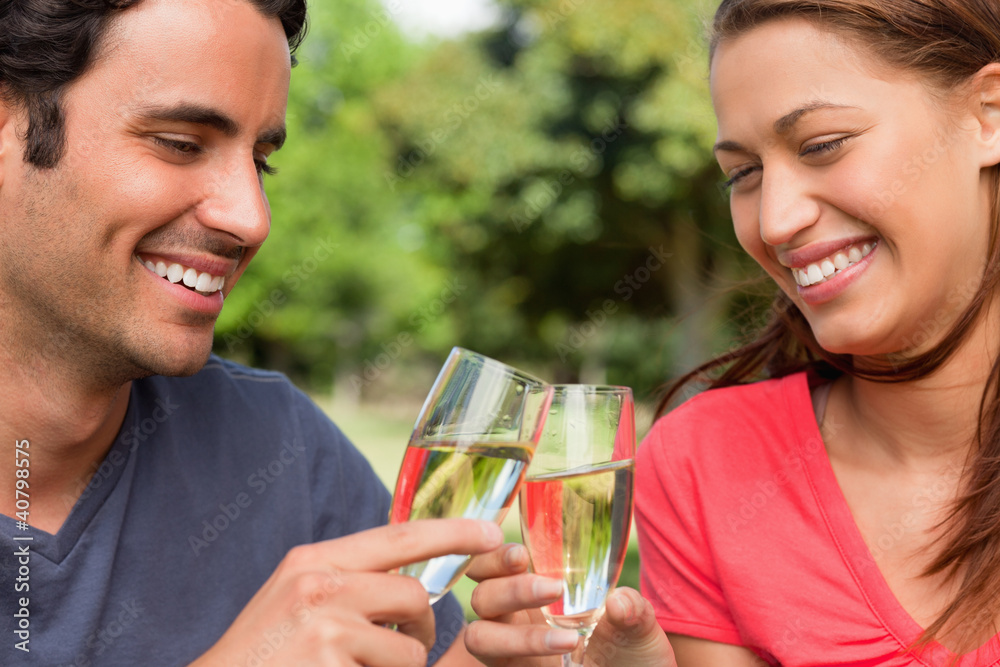 Two friends smiling as they touch glasses of champagne together Two friends smiling as they touch glasses of champagne together