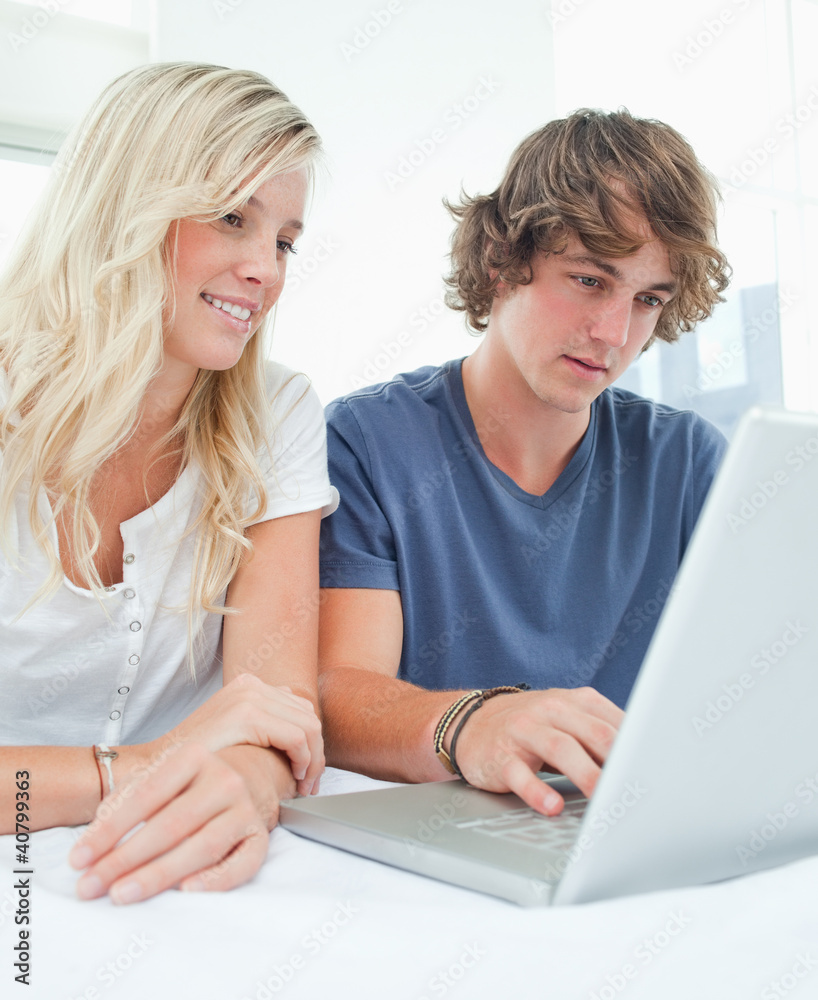 A smiling couple sitting and using the laptop A smiling couple sitting and using the laptop