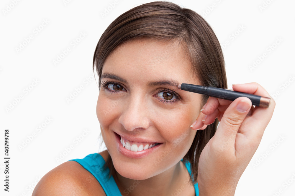 Young female using an eyebrow pencil to make-up Young female using an eyebrow pencil to make-up