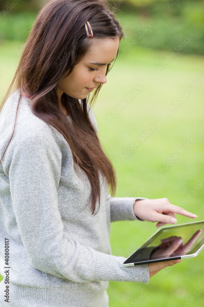 Young relaxed girl standing upright in a park while holding a ta Young relaxed girl standing upright in a park while holding a ta