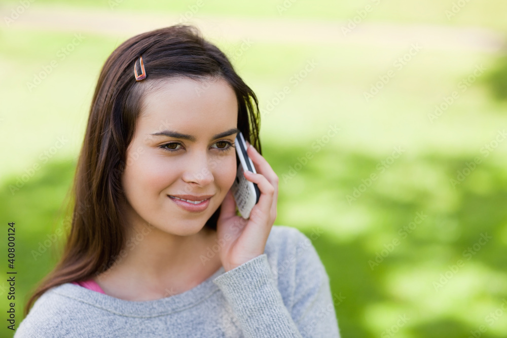Young relaxed girl talking on the phone while standing in the co Young relaxed girl talking on the phone while standing in the co