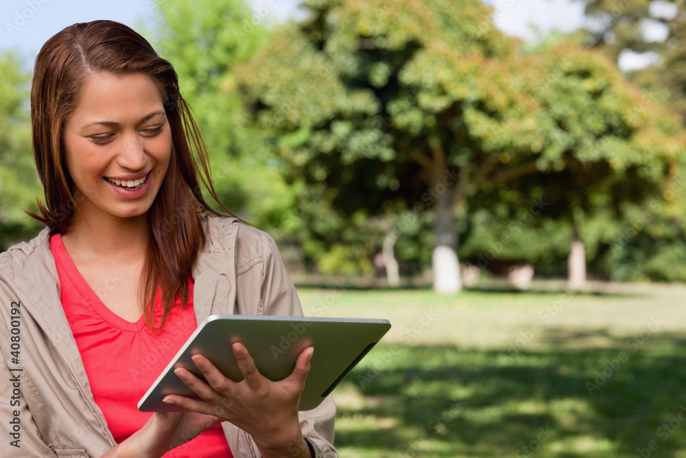 Young woman smiling enthusiastically while using a tablet Young woman smiling enthusiastically while using a tablet