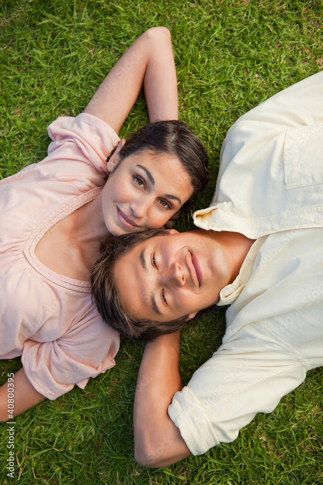 Woman looking upwards while lying head to shoulder with her frie Woman looking upwards while lying head to shoulder with her frie