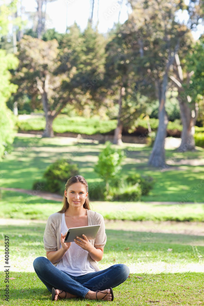 Woman sitting on the lawn while using her tablet Woman sitting on the lawn while using her tablet