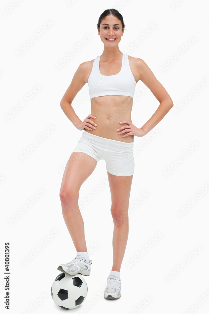 Slim young woman smiling in white clothes holding a soccer ball