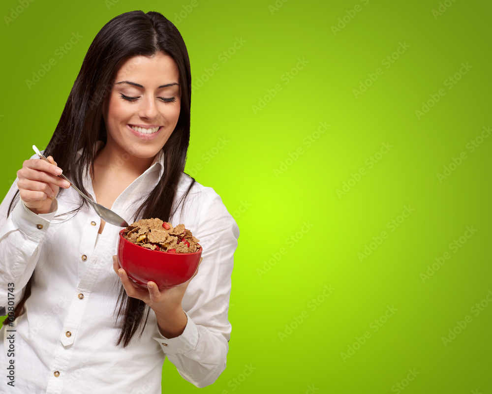 portrait of healthy young woman eating cereals over green