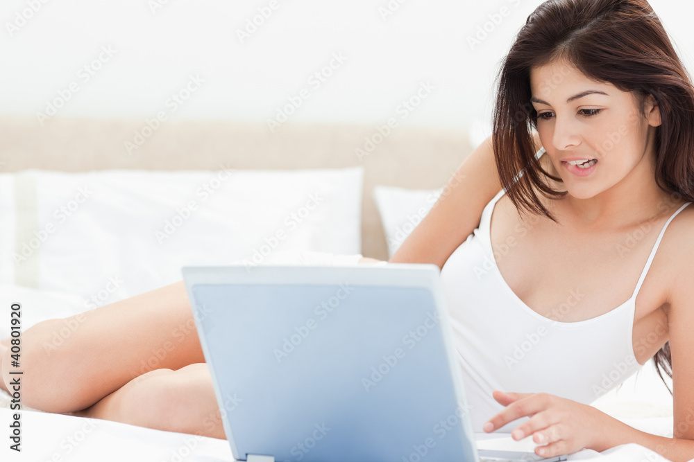 Woman lying on bed while watching and enjoying whats on her lapt Woman lying on bed while watching and enjoying whats on her lapt
