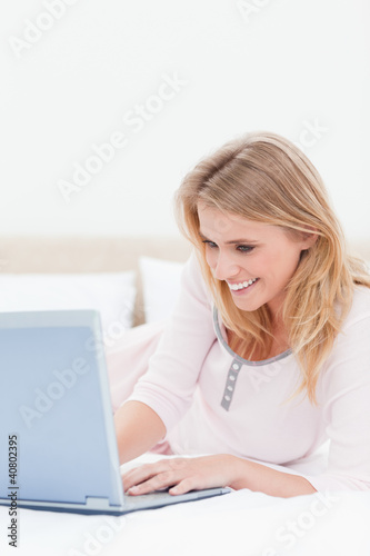 Close up, Woman using a laptop while on the bed and smiling