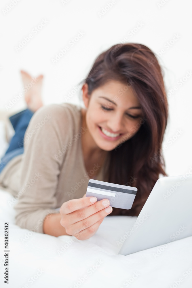 Close up, focusing on credit card, held by a smiling woman on he Close up, focusing on credit card, held by a smiling woman on he