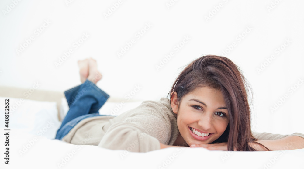 Low angle, woman lying on the bed, smiling with her legs crossed Low angle, woman lying on the bed, smiling with her legs crossed
