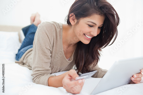 Woman using a tablet with her credit card, and smiling while lyi photo
