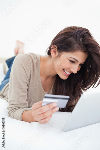 Woman smiling as she uses her tablet and credit card