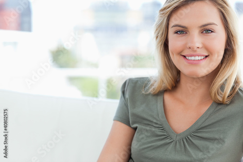 Close up, woman smiling as she sits on a couch
