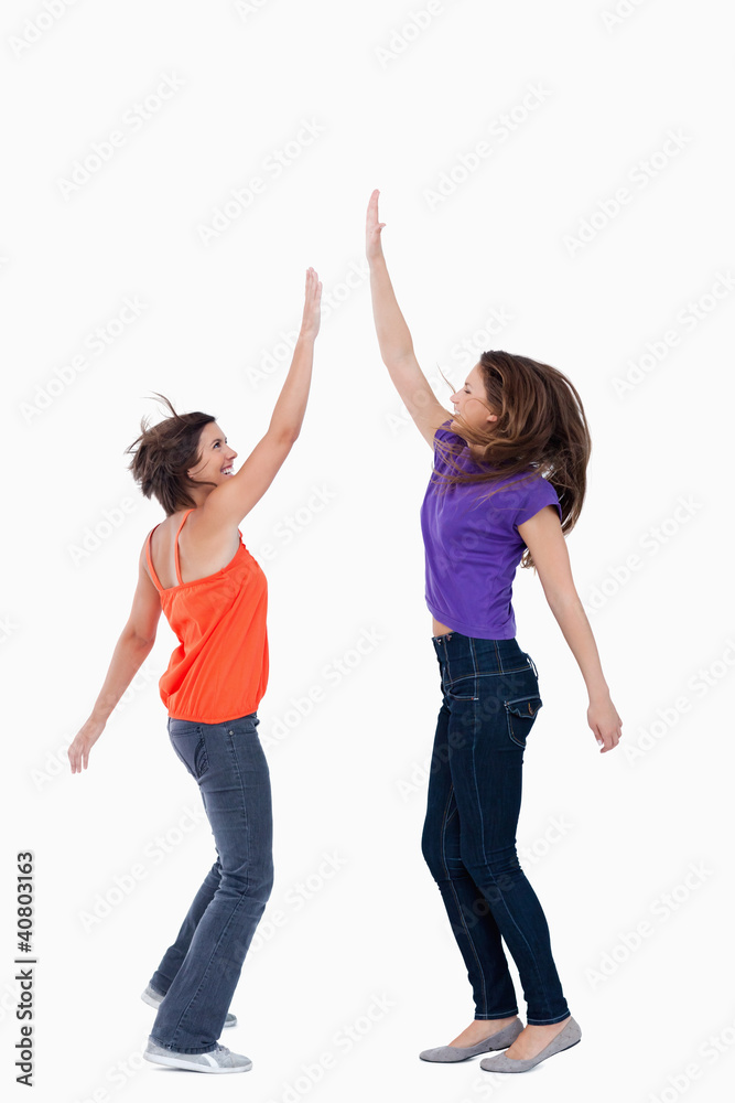 A teenage girl keeping her hand in the air while her best friend A teenage girl keeping her hand in the air while her best friend