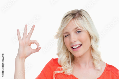 Young blonde woman showing the OK sign and a blink of an eye